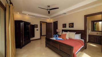 A hotel room with a bed, a ceiling fan, a television, and a bathroom with a mirror.