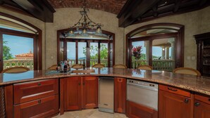 A spacious kitchen with a large island, wooden cabinetry, and a view of the outdoors. - Los Suenos Luxury Villas by Stay in Costa Rica (Los Sueños)