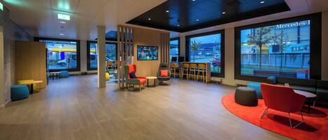 A modern lounge area with seating and a large screen displaying a cityscape.