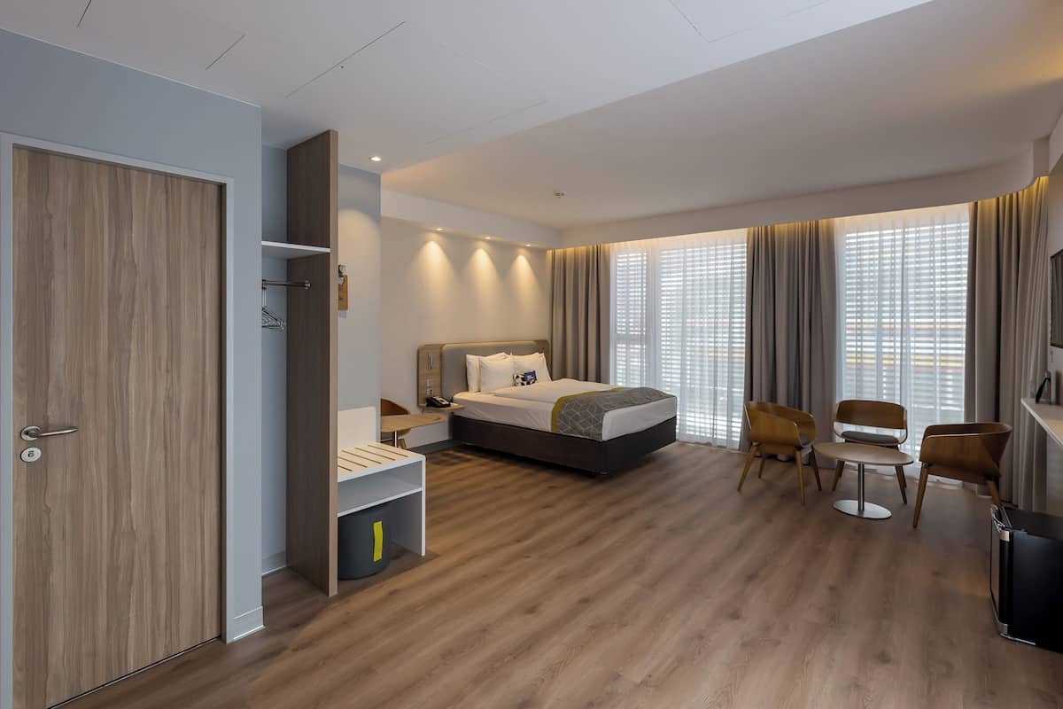 Ein modernes Hotelzimmer mit Bett, Schreibtisch, Stuhl und Fernseher.