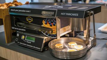 Une machine à crêpes automatique avec écran numérique et surface de cuisson en acier inoxydable.