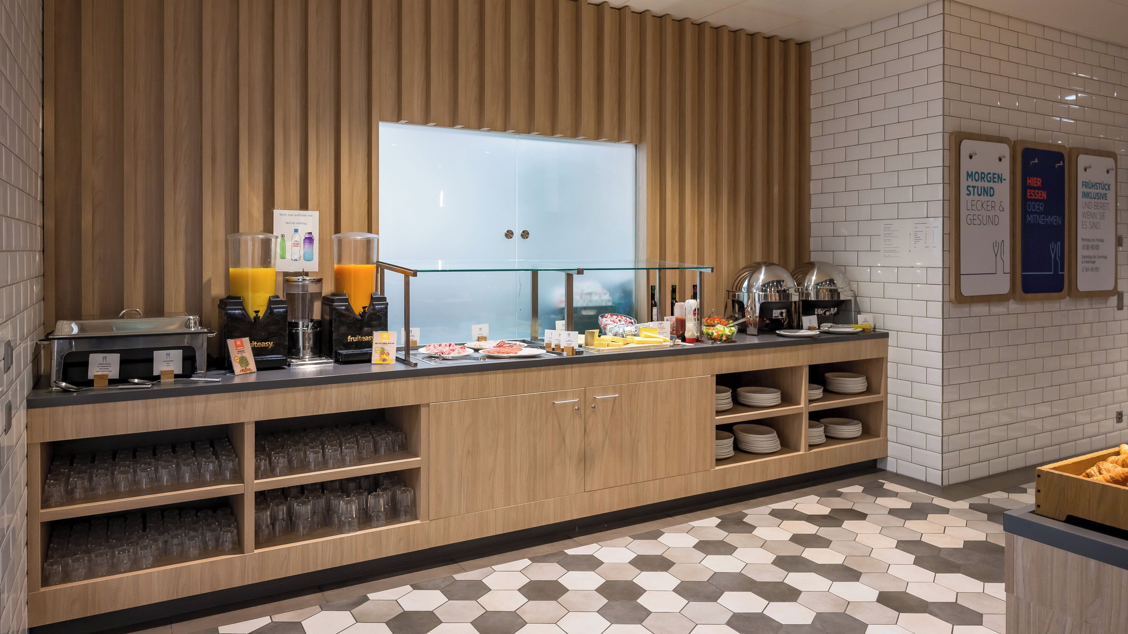 A breakfast bar with juice dispensers, a coffee machine, and a variety of food items.