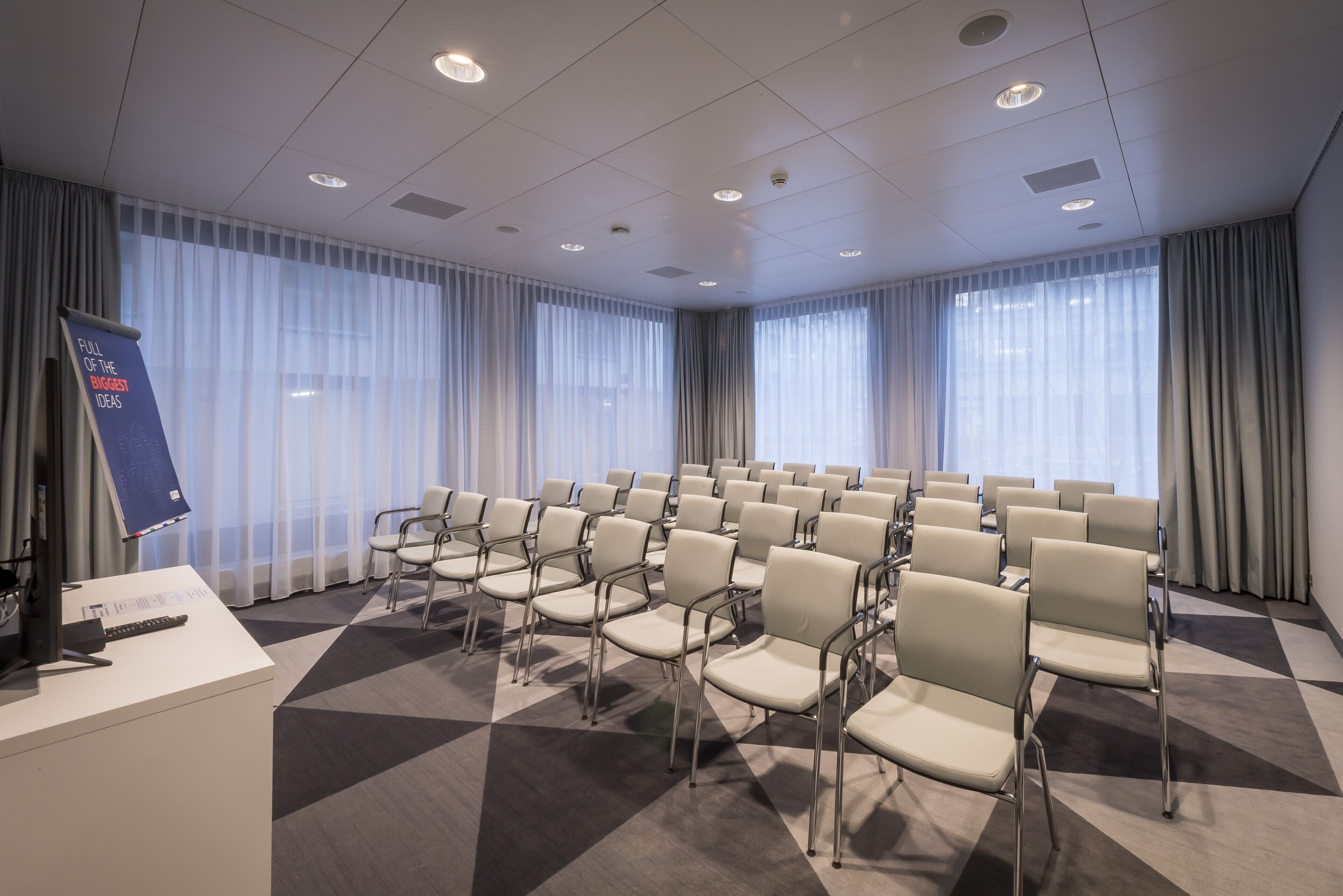 Une salle de conférence avec des rangées de chaises, un pupitre et une banderole.