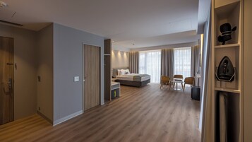 Una habitación de hotel moderna con cama, mesita de noche y una zona de estar con sillas.