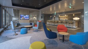 Un espace de détente moderne, doté de sièges, d’un bar et d’un écran de télévision.
