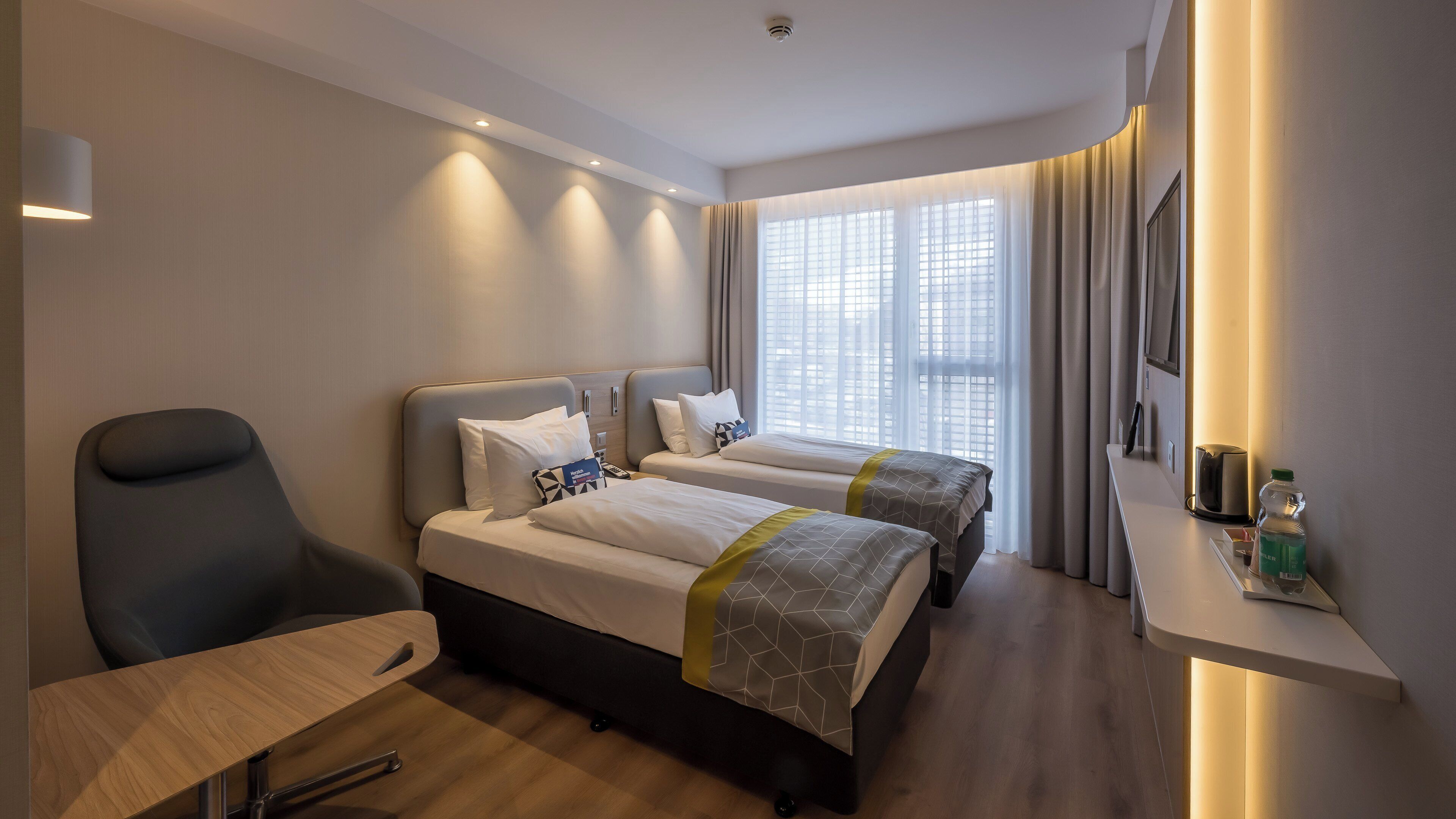 Une chambre d’hôtel avec deux lits, un bureau, une chaise et un minibar.