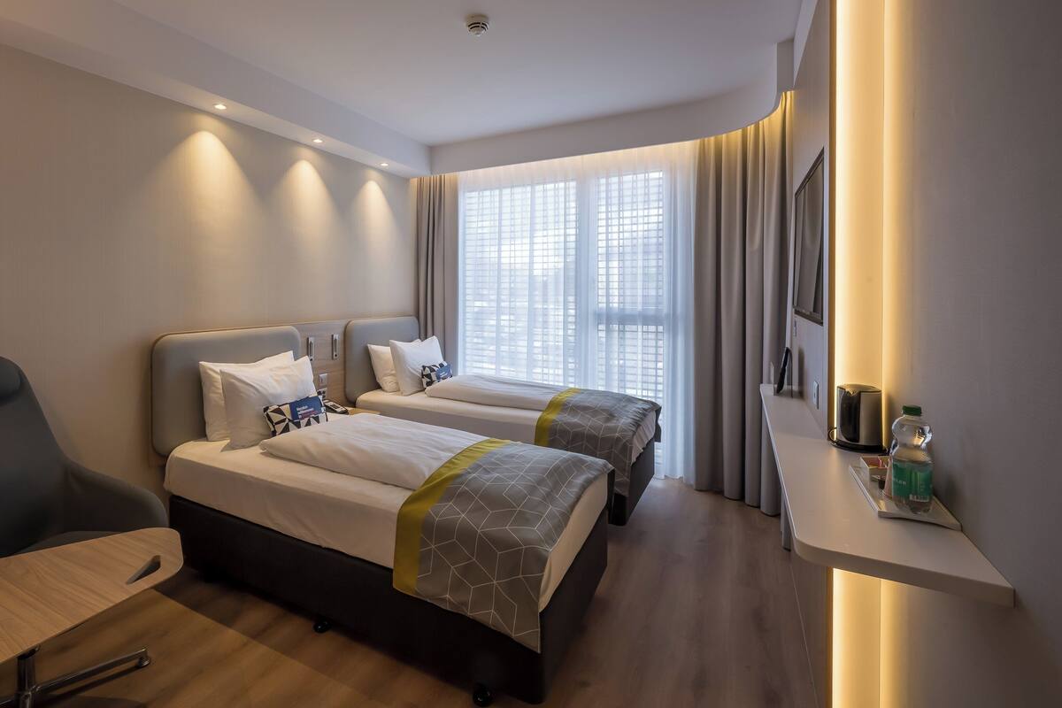 Ein Hotelzimmer mit zwei Betten, einem Schreibtisch, einem Stuhl und einer Minibar.