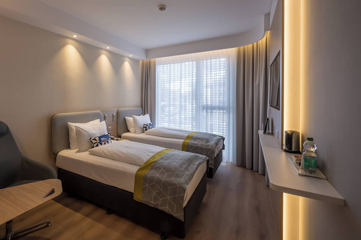 Une chambre d’hôtel avec deux lits, un bureau, une chaise et un minibar.