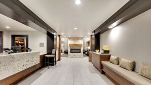 Vestíbulo de hotel con mostrador de recepción, zona de estar y chimenea.