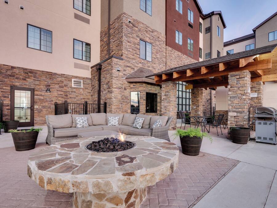 A courtyard with a stone fire pit, outdoor seating, and a barbecue grill.