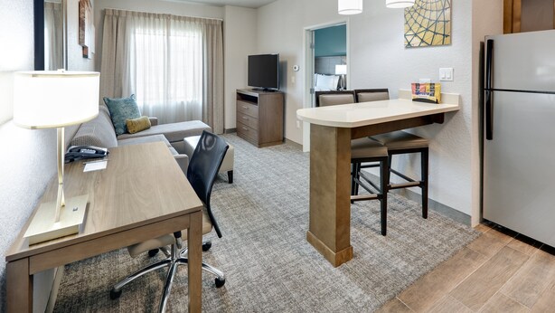 A compact hotel room with a kitchenette, a dining area, a sofa, and a TV. - Staybridge Suites San Antonio - Schertz  by IHG (Schertz)