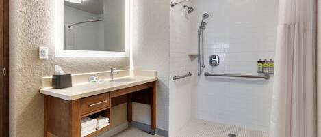 A bathroom with a wooden vanity, a mirror, a shower with a glass door, and a towel rack.