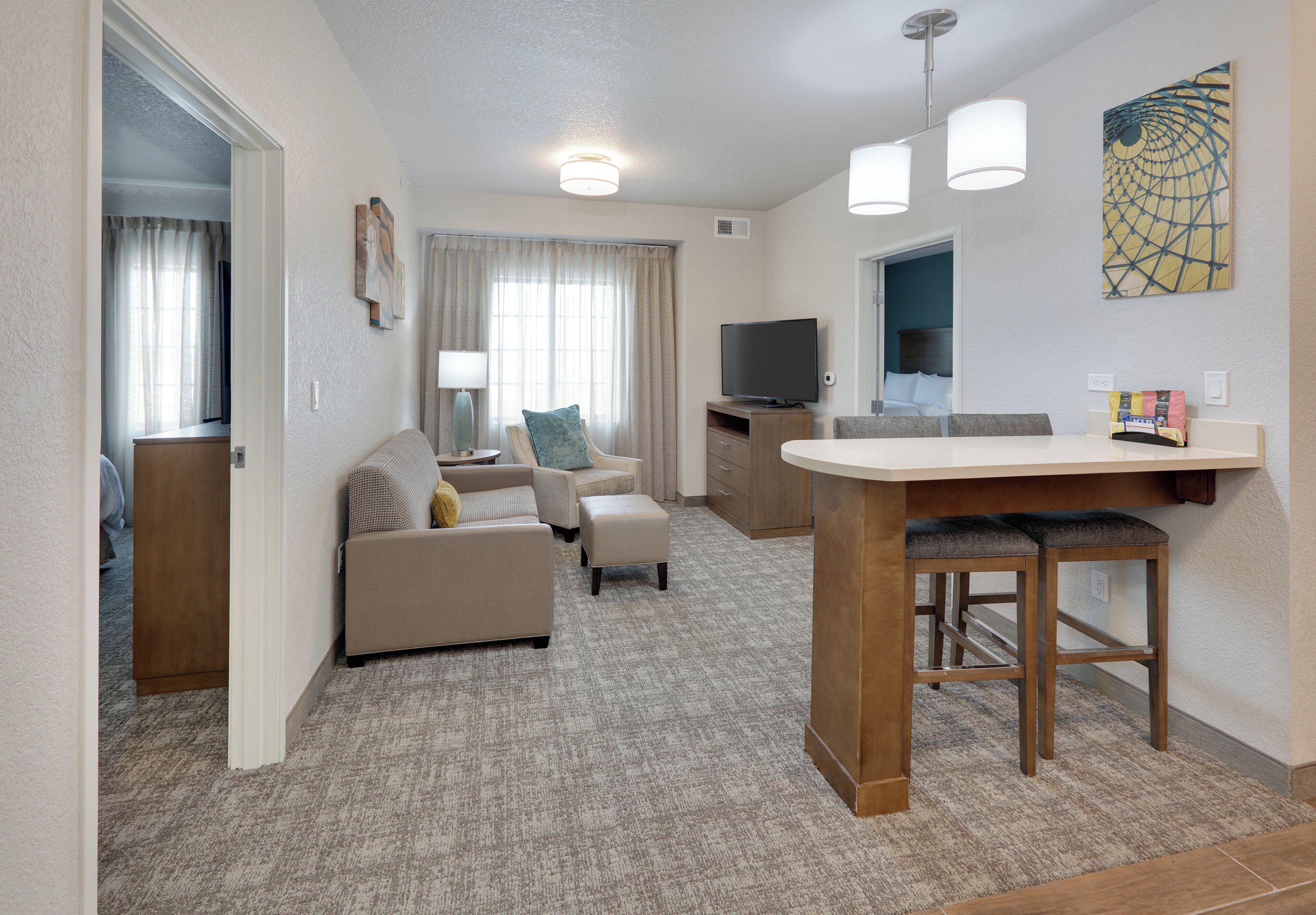 A compact living space with a kitchenette, a sofa set, a dining area, and a television.
