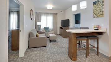 A compact living space with a kitchenette, a sofa set, a dining area, and a television.
