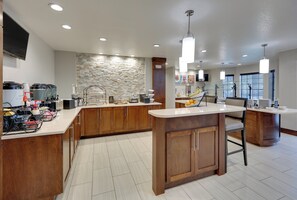 A modern kitchen with wooden cabinets, a stone backsplash, and a central island. - Staybridge Suites San Antonio - Schertz  by IHG (Schertz)