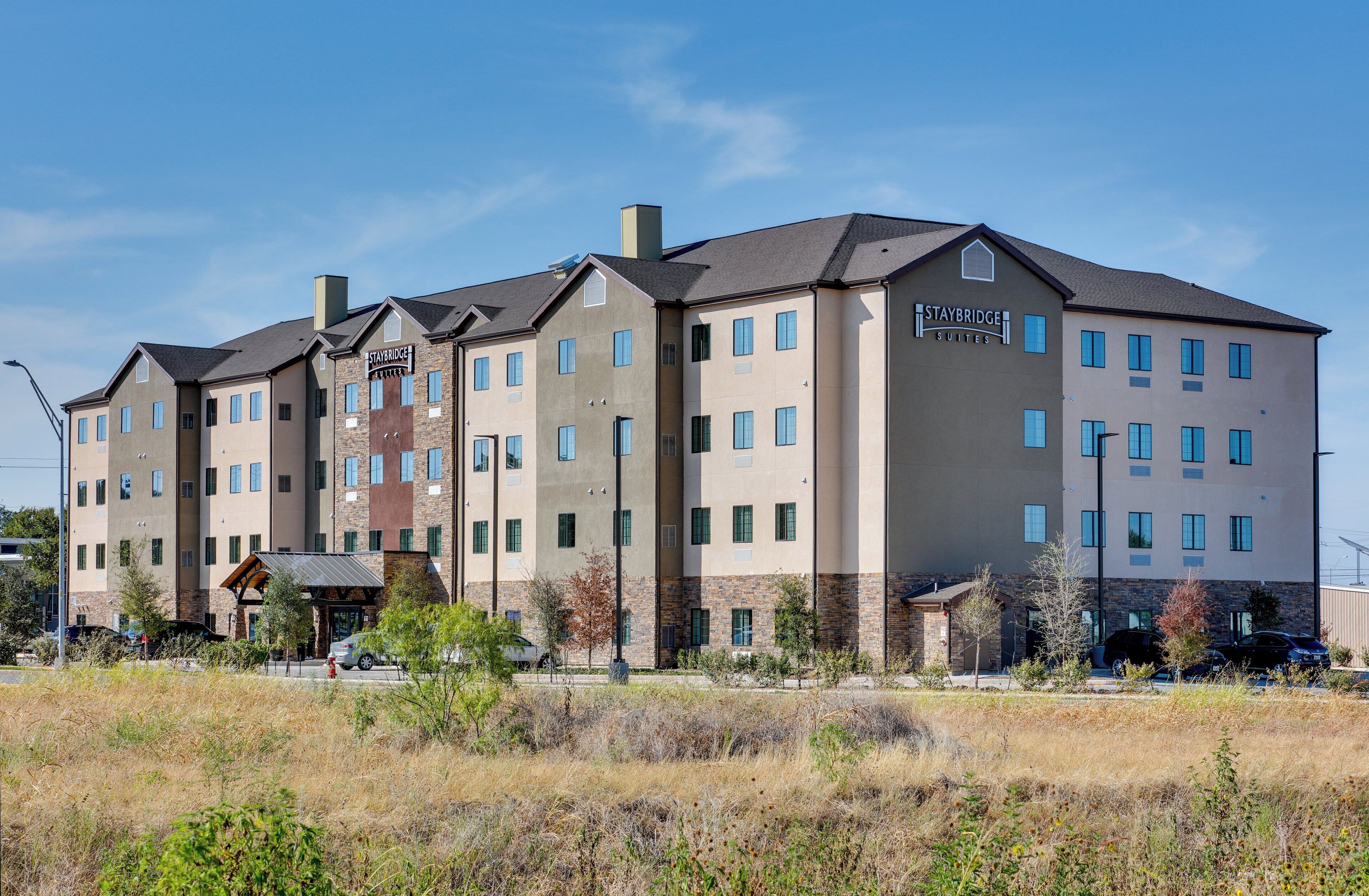 A multi-story hotel with a stone facade, multiple windows, and a sign indicating it is a Staybridge Suites hotel.