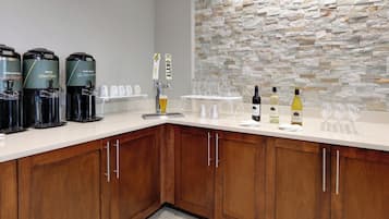 Un espace bar équipé de machines à café, d’une tireuse marquée du chiffre « 4 » et de bouteilles de vin.