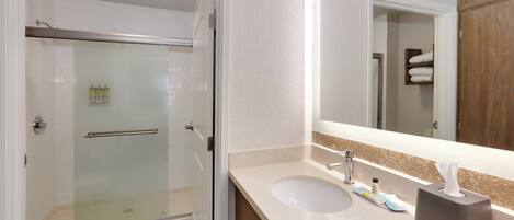 A modern bathroom with a glass-enclosed shower, a white sink, and a large mirror.