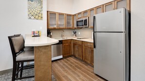 A compact kitchen with wooden cabinets, a stainless steel refrigerator, a microwave, and a sink. - Staybridge Suites San Antonio - Schertz  by IHG (Schertz)