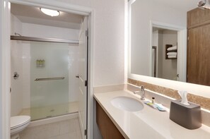 A modern bathroom with a glass-enclosed shower, a white sink, and a mirror above it. - Staybridge Suites San Antonio - Schertz  by IHG (Schertz)