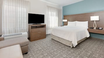Una habitación de hotel con cama, televisor, escritorio con lámpara y una silla.