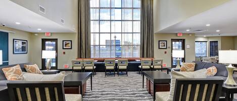 A hotel lobby with a large window, multiple seating areas, and exit signs.