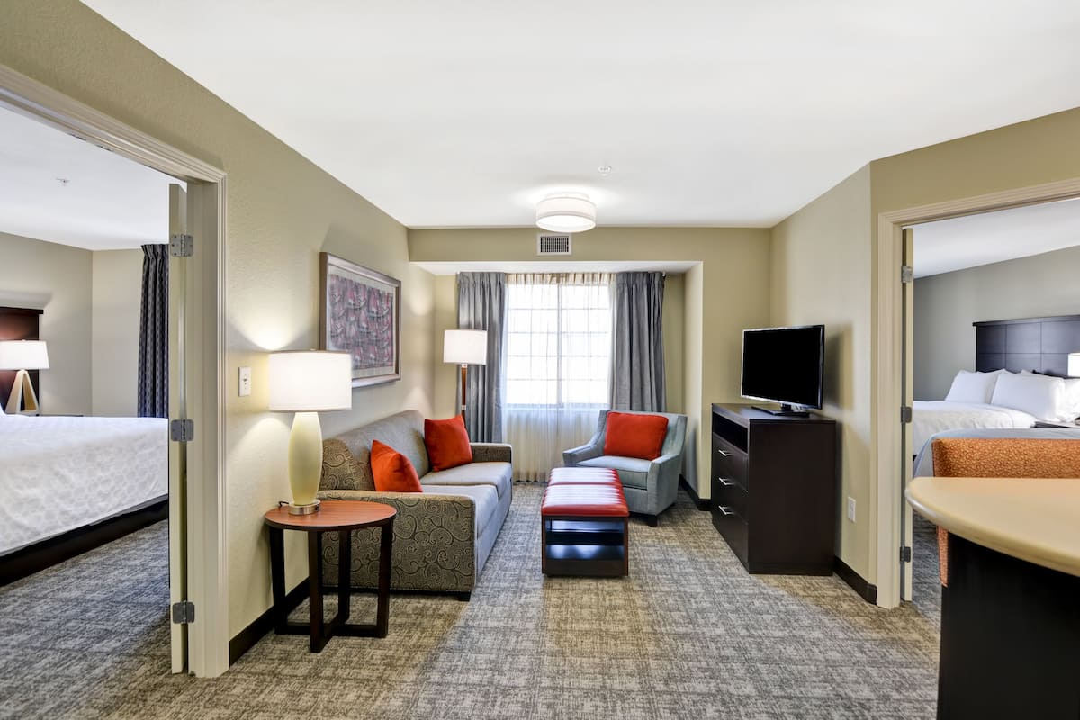 A hotel room with a bed, a sofa, a chair, a TV, and a desk.