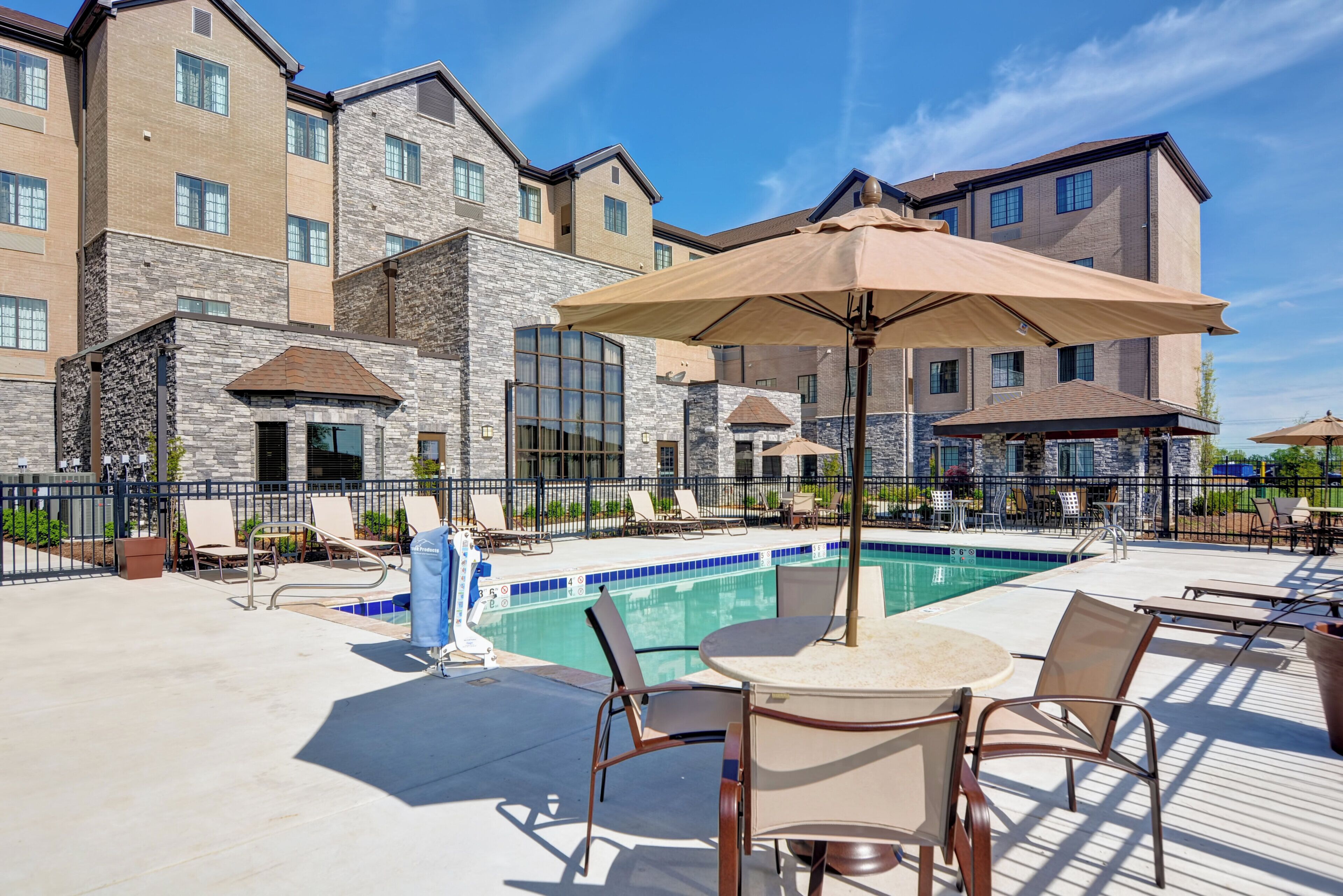 A poolside area with lounge chairs, a table, and umbrellas.