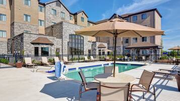 A poolside area with lounge chairs, a table, and umbrellas.