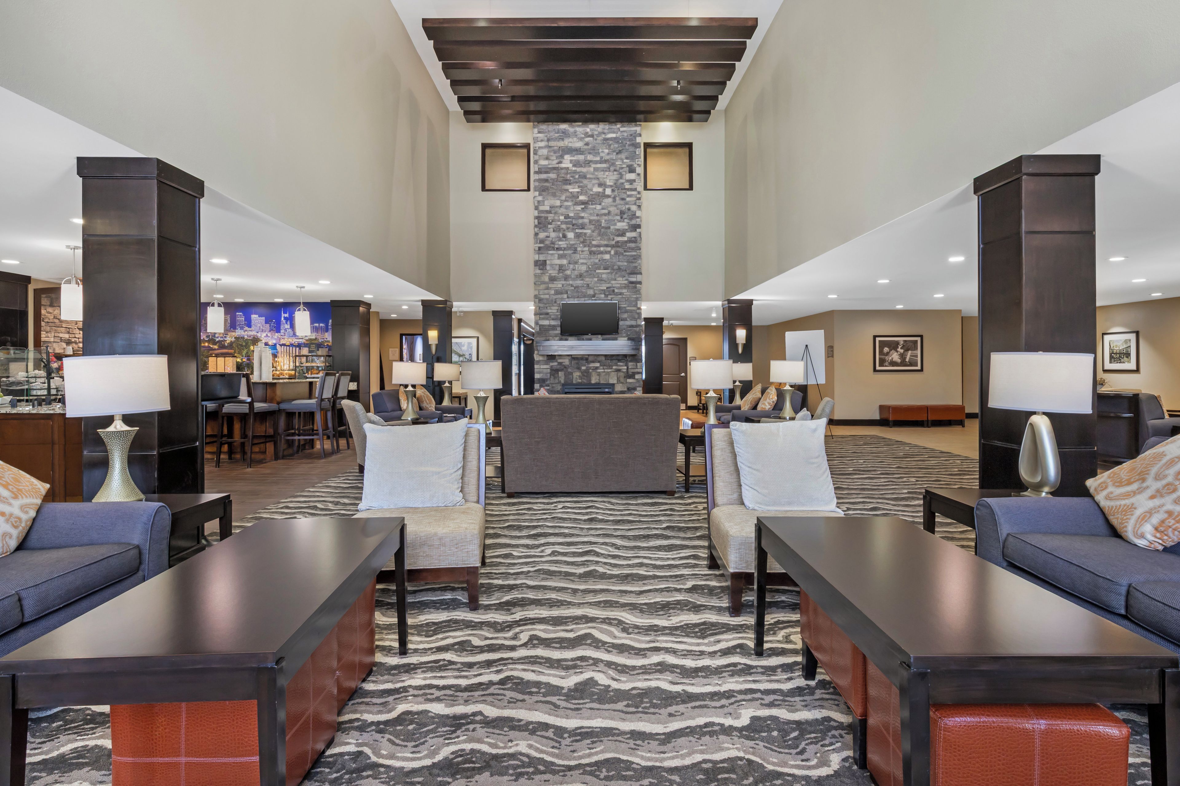 A hotel lobby with a central seating area, a fireplace, and a cityscape mural on the wall.