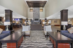 A hotel lobby with a central seating area, a fireplace, and a cityscape mural on the wall.