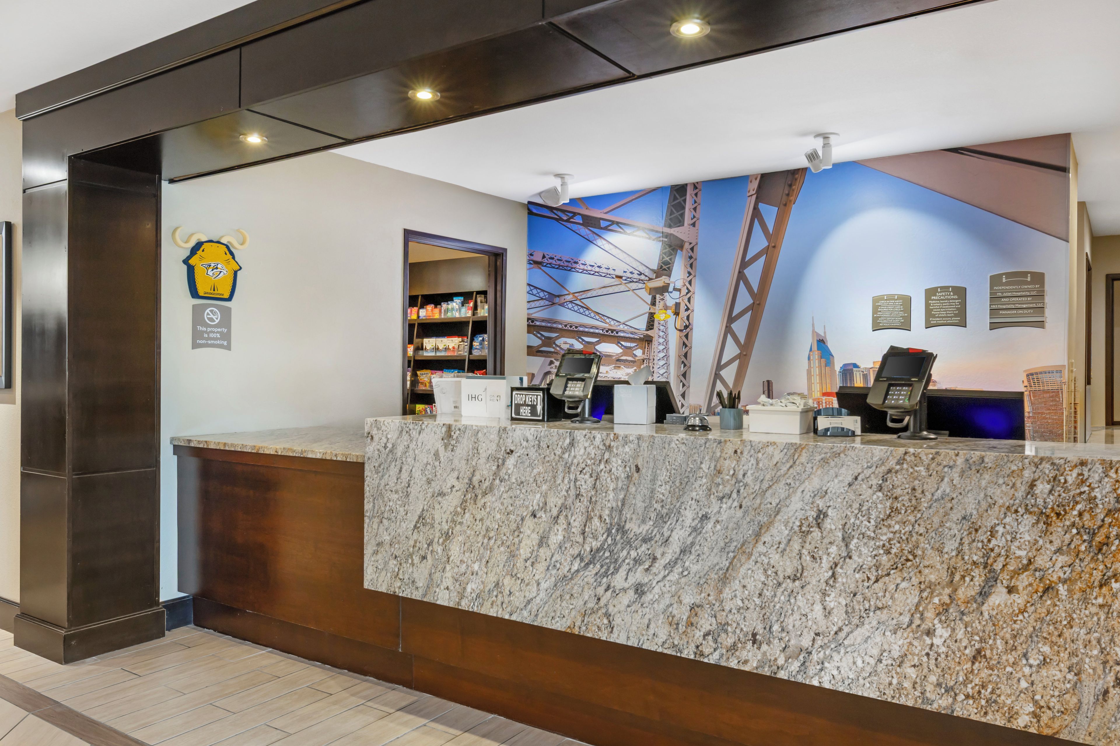 A hotel reception desk with a marble counter, a security camera, and a non-smoking sign.
