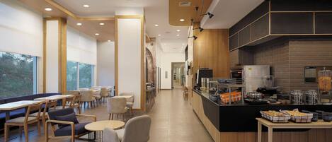 A modern cafe with a long counter, seating area, and large windows.
