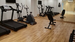 Un gimnasio con diverso equipo de ejercicio, incluyendo cintas de correr, bicicletas estáticas y elípticas.