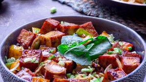 Un tazón de comida con tofu, verduras y hierbas.