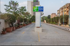 A Holiday Inn Express sign in front of a building with a paved walkway and potted plants. - Holiday Inn Express Pune Hinjewadi by IHG (Paud)