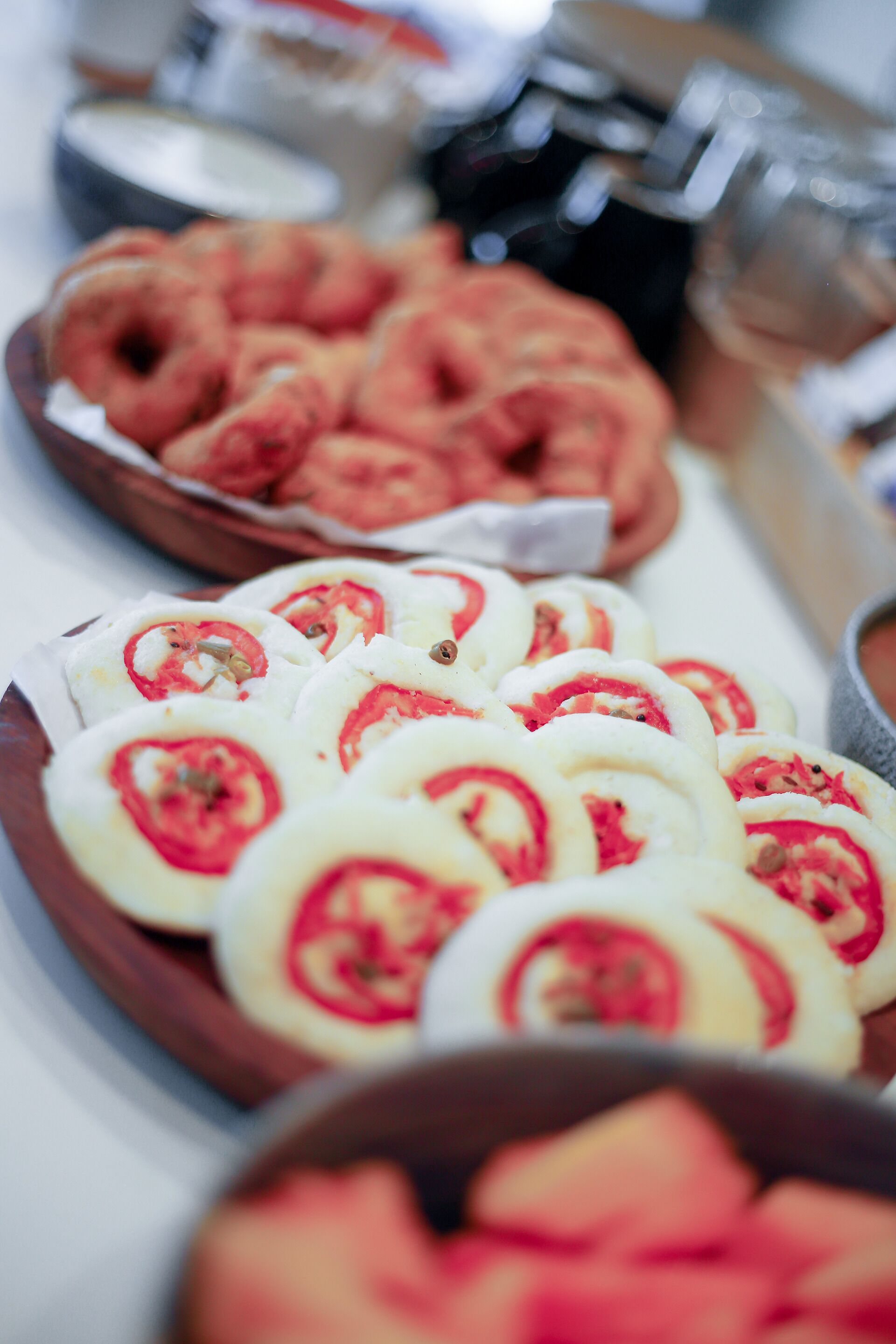 A buffet table with various food items, including sliced tomatoes and a bowl of pastries.