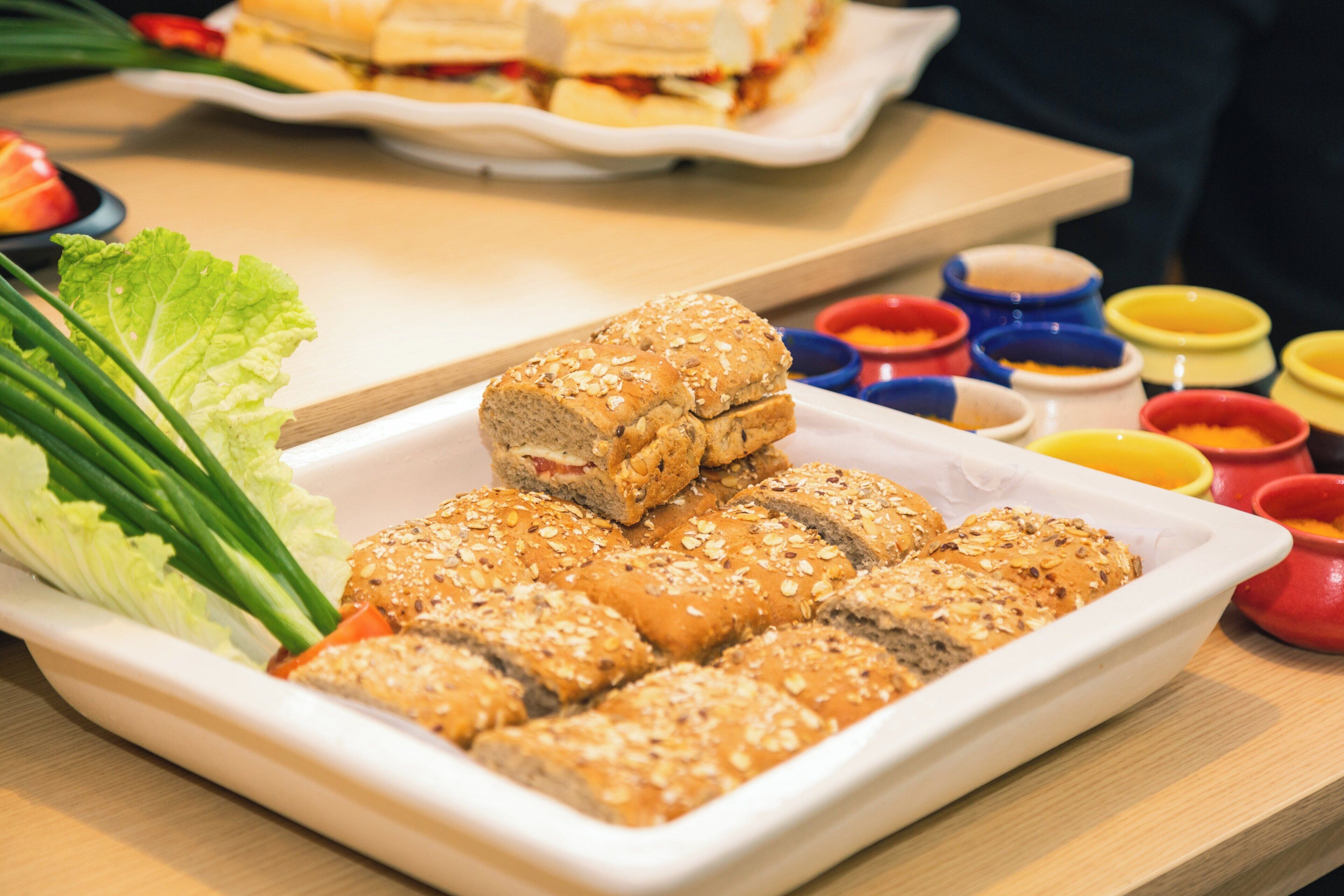 A white rectangular plate with sliced sandwiches and a side of green lettuce.
