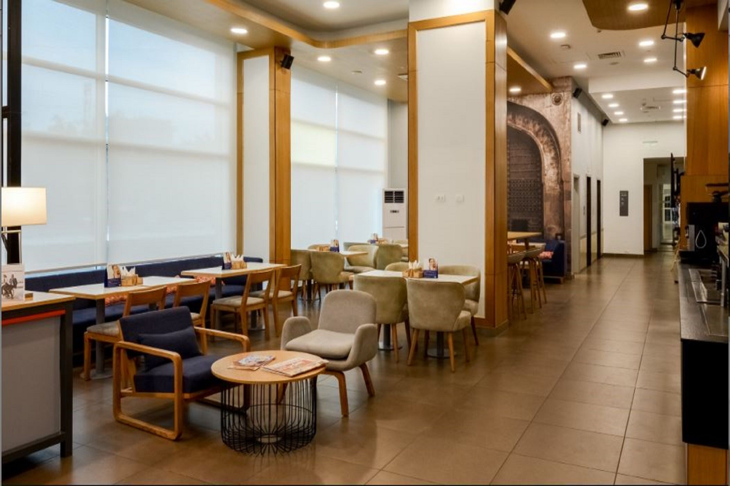 Um restaurante com cabines e mesas, uma parede de tijolos e um balcão iluminado por um abajur.