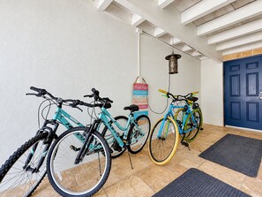A hallway with bicycles parked against the wall, a blue door, and a hanging lantern.