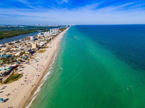 Modern Hollywood Beach villa with a private heated saltwater pool, hot tub, and spacious family-friendly layout. Just 1 mile from the ocean & Broadwalk, featuring a full kitchen, open living areas, and tropical outdoor lounge spaces.