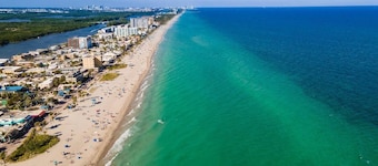 Modern Hollywood Beach villa with a private heated saltwater pool, hot tub, and spacious family-friendly layout. Just 1 mile from the ocean & Broadwalk, featuring a full kitchen, open living areas, and tropical outdoor lounge spaces.