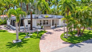 A modern building with a paved driveway, surrounded by palm trees and a well-maintained lawn. - Spacious Oasis -Heated Pool, Hot Tub & Near Beach (Hollywood)