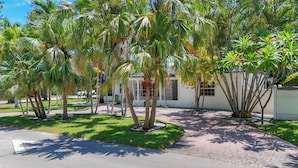 A paved walkway surrounded by palm trees and a building with a white facade.