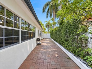 A pathway leading to a building with large windows and a white exterior.