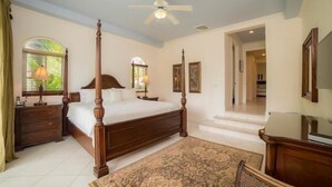 A four-poster bed with a wooden frame, a ceiling fan, and a large window with blinds. - Los Suenos Resort Colina 8E (Jacó)