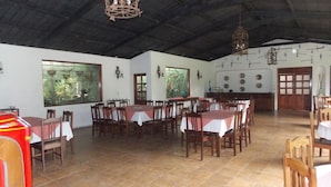 Un comedor amplio con varias mesas y sillas, ventanas grandes y un techo alto con vigas a la vista.