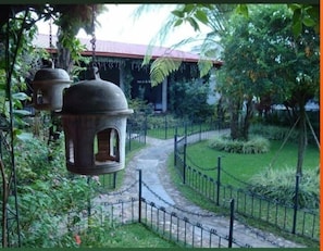 A pathway leading to a building with a red roof, surrounded by greenery and a chain-link fence. - Hotel Casa Duranta (Cobán)