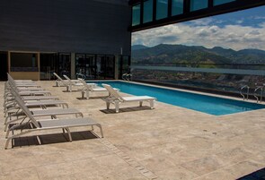Una piscina al aire libre, sombrillas, sillones reclinables de piscina