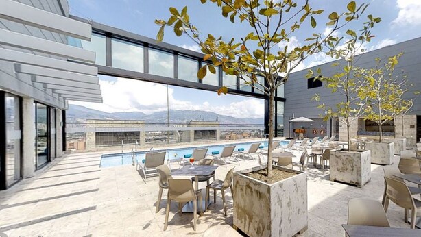 A rooftop bar with outdoor seating, a pool, and a view of mountains. - Estelar Square (Medellín)